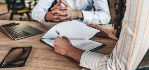 Gros plan d'une main féminine signant un document formel sur la table d'un bureau